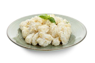 Beyaz arka planda krem soslu lezzetli gnocchi tabağı.