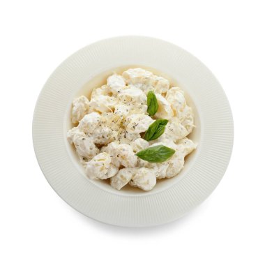 Beyaz arka planda krem soslu lezzetli gnocchi tabağı.