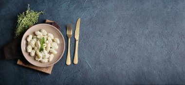 Siyah arkaplanda krema soslu lezzetli gnocchi tabağı.