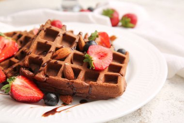 Masada böğürtlen ve bademli lezzetli çikolatalı waffle tabağı, yakın plan.