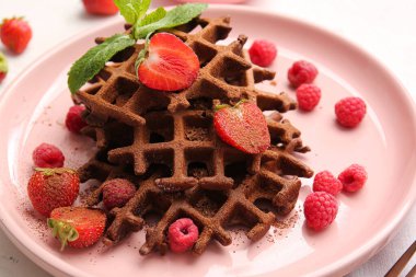 Beyaz arka planda böğürtlenli leziz çikolatalı Belçika Waffle tabağı.