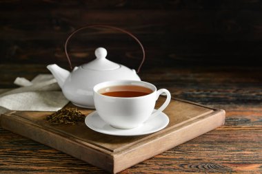 Tahta tahtada bir fincan lezzetli hojicha yeşil çay ve demlik var.