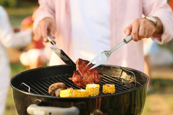 Senior man cooking food on barbecue grill outdoors