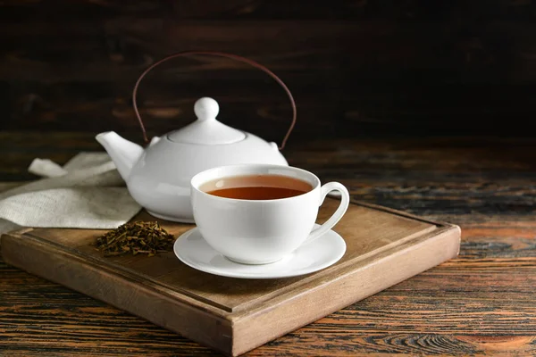 おいしいほうじ茶のカップと木製のボードテーブルの上の緑茶とポット — ストック写真