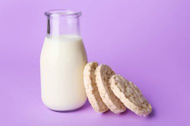 Kabarmış pirinç krakerleri ve arka planda bir şişe süt.