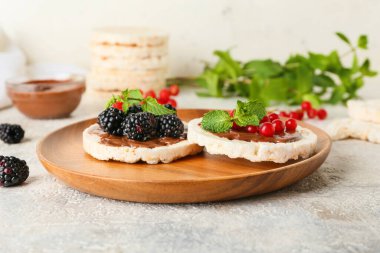Pofuduk pirinç kraker ve hafif arka planda böğürtlen tabağı, yakın plan.