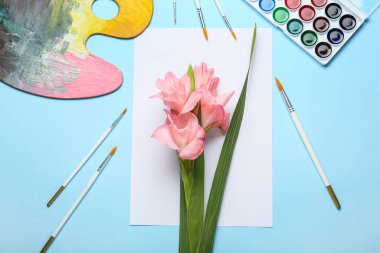 Göz kamaştırıcı gladiolus çiçekleri, renkli arka planda boya ve fırçalar