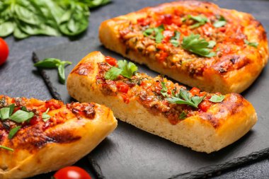 Siyah zemin üzerinde dilimlenmiş Türk Pizzası olan tahta