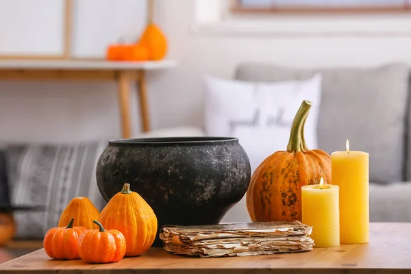 Witch\'s cauldron with candles and pumpkins on table in room