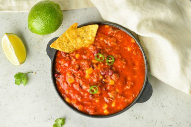 Lezzetli kırmızı biberli tava, nachos ve hafif arkaplanda limon.