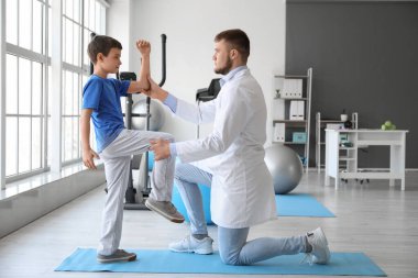 Fizyoterapist rehabilitasyon merkezinde bir çocukla çalışıyor.