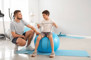 Fizyoterapist rehabilitasyon merkezinde bir çocukla çalışıyor.