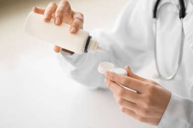 Kontak lensleri ve klinikte bir şişe çözeltisi olan oftalmolog.