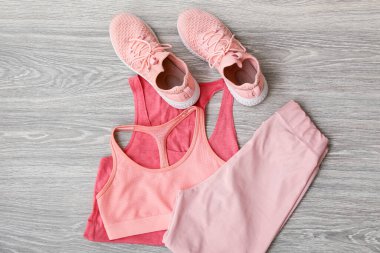 Spor kıyafetleri ve hafif ahşap arka planda ayakkabılar.