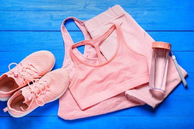 Spor giysileri, ayakkabılar ve su şişesi renkli ahşap arka plan