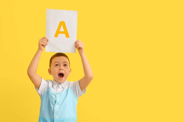 Kleiner Junge Hält Papierbogen Mit Buchstabe Auf Farbigem Hintergrund — Stockfoto