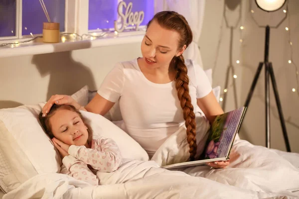 母とともに本と彼女の眠っている小さな娘でベッドルーム — ストック写真