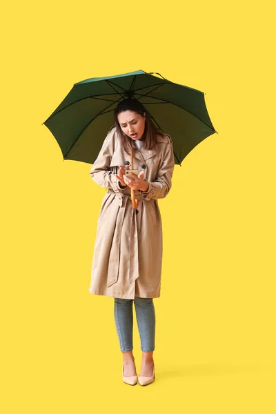 Schöne Junge Frau Mit Regenschirm Und Handy Auf Farbigem Hintergrund — Stockfoto