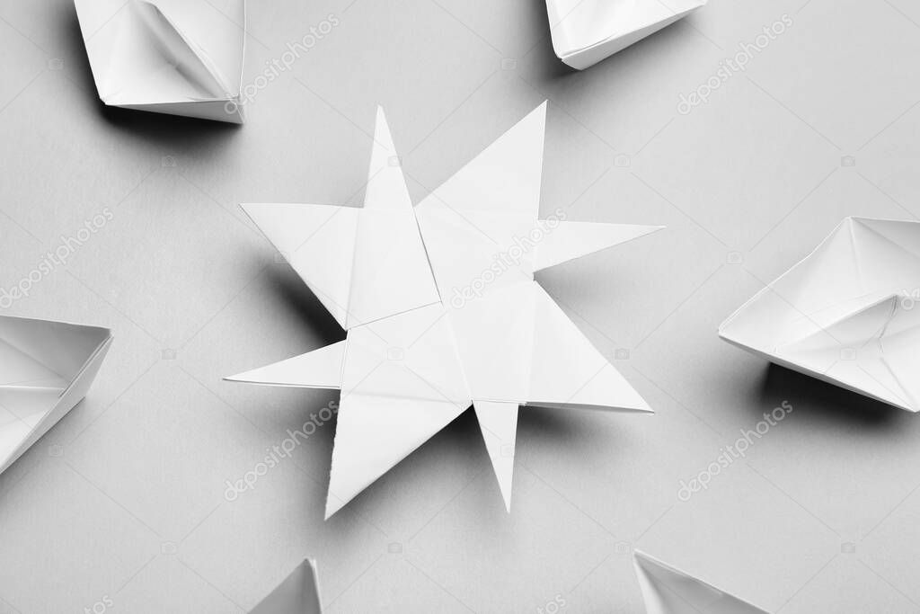 Paper and wind rose with origami boats on grey background