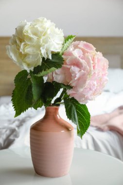 Yatak odasındaki masada ortanca çiçekli vazo.