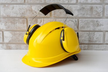 Tuğla arka planda kulak koruyucuları olan sert şapka