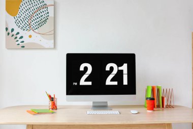 Modern bilgisayarlı işyeri, bir fincan kahve ve kırtasiye malzemeleri ışık duvarının yanındaki masada.