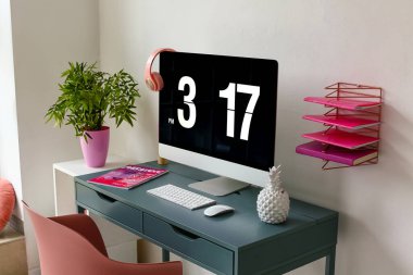 Modern bilgisayar, dergi ve dekorla beyaz duvarın yanında şık bir iş yeri.