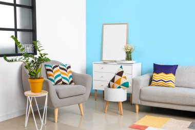 Rahat kanepe ve koltuk, boş poster çerçevesi. Renkli oturma odasının iç tarafındaki çekmeceler.