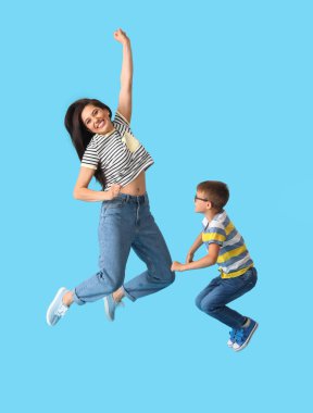 Zıplayan genç kadın ve küçük oğlu renkli arka planda