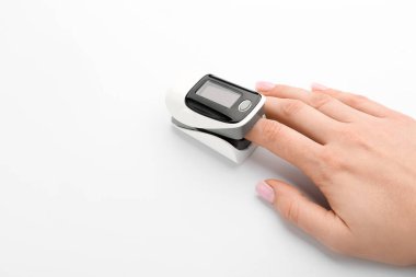 Beyaz arka planda nabız oksimetresi olan kadın.