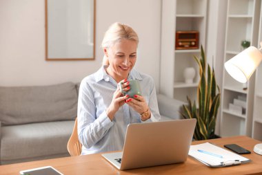 Ofiste kahve içen olgun bir kadın.