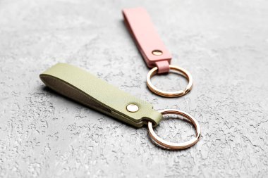 Gri arkaplanda deri anahtarlıklar, yakın plan.