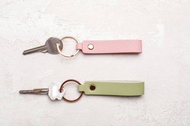 Açık arkaplanda deri anahtarlıkları olan anahtarlar