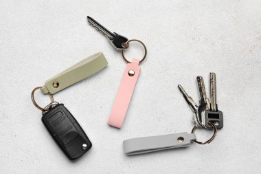 Açık arkaplanda deri anahtarlıkları olan anahtarlar