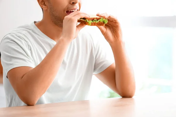 Jeune Homme Mangeant Sandwich Savoureux Dans Cuisine — Photo