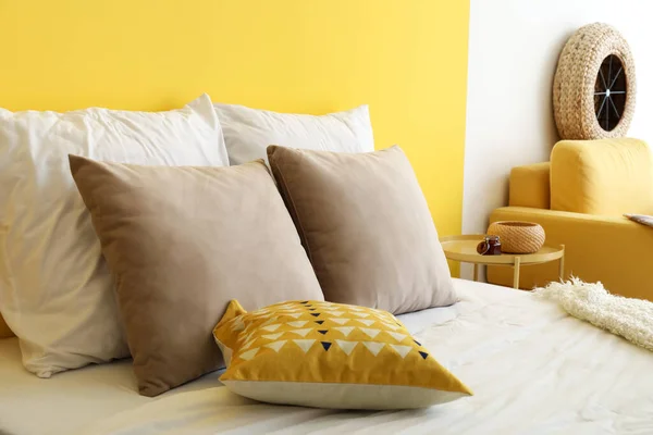 柔らかい枕と黄色の壁の近くの毛布付きの快適なベッド — ストック写真