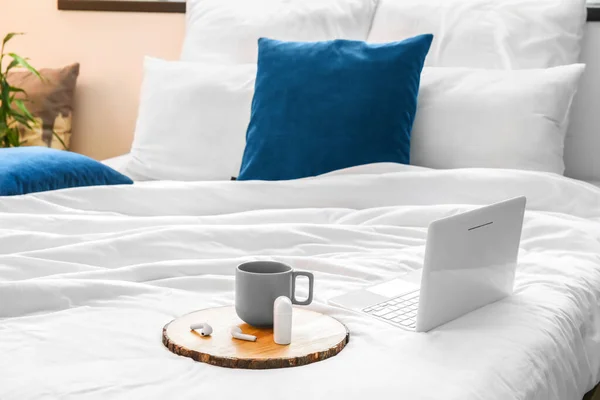 柔らかいベッドの上でカップやイヤフォン ラップトップでトレイ — ストック写真