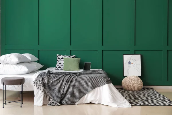 Dizüstü bilgisayarı, divanı ve renkli duvarı olan rahat bir yatak.