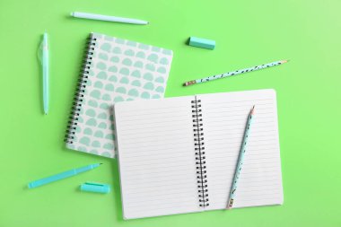 Renk arkaplanındaki defterler, kalemler ve silgi