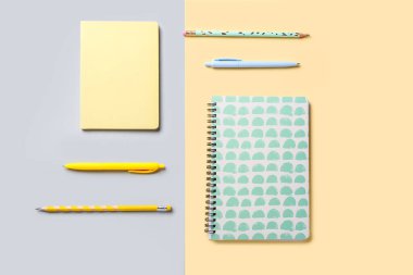Renkli arkaplan üzerinde şık not defterleri, kalemler ve kalemler