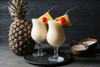 Ahşap zemin üzerinde lezzetli Pina Colada kokteyli olan bardaklar