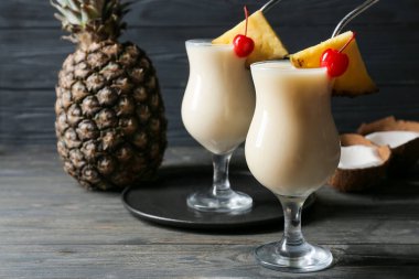 Ahşap zemin üzerinde lezzetli Pina Colada kokteyli olan bardaklar