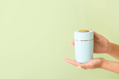 Renk arka planında modern hava nemlendiricisi olan kadın elleri