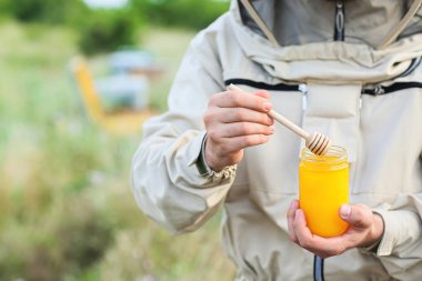Arı kovanında kavanozda bal taşıyan arıcı.