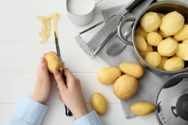 Hafif ahşap arka planda patates püresi hazırlayan kadın, yakın plan.