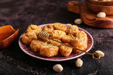 Lezzetli baklava ve bal kaplamalı tabak koyu arkaplanda yapışmış.