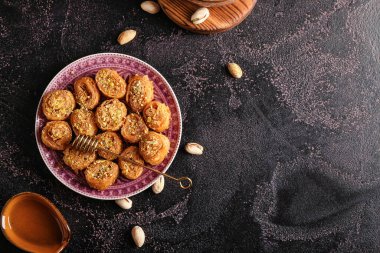 Lezzetli baklava ve bal kaplamalı tabak koyu arkaplanda yapışmış.