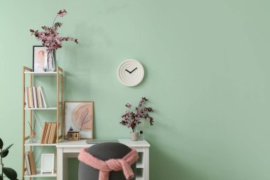 Renk duvarının yanında çiçek açan dalları olan şık bir iş yeri.