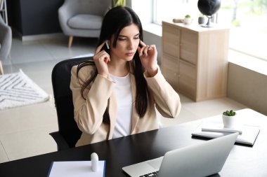 Ofiste görüntülü konuşmadan önce kulaklık takan güzel bir iş kadını.