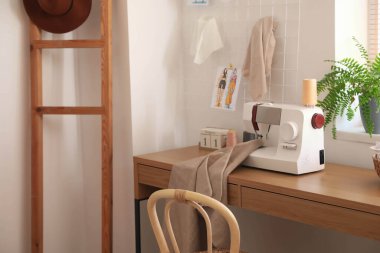 Terzi atölyesinde dikiş makinesi ve kumaş olan masa.